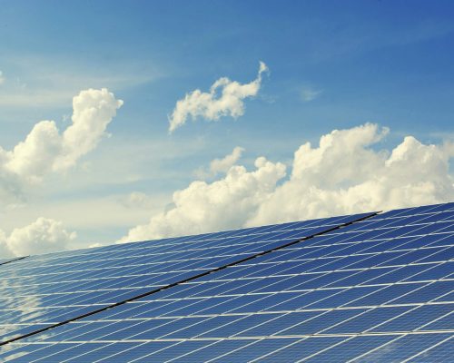 Sleek modern solar panels under a vibrant blue sky with clouds, symbolizing clean energy.